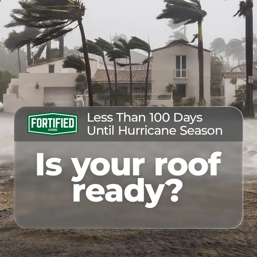 A coastal house with palm trees bends under heavy wind and rain. Overlaid text reads, "Less Than 100 Days Until Hurricane Season. Is your roof ready?" Above the text is a Fortified Home logo. The image suggests preparing and fortifying roofs for hurricane season with roofing solutions.